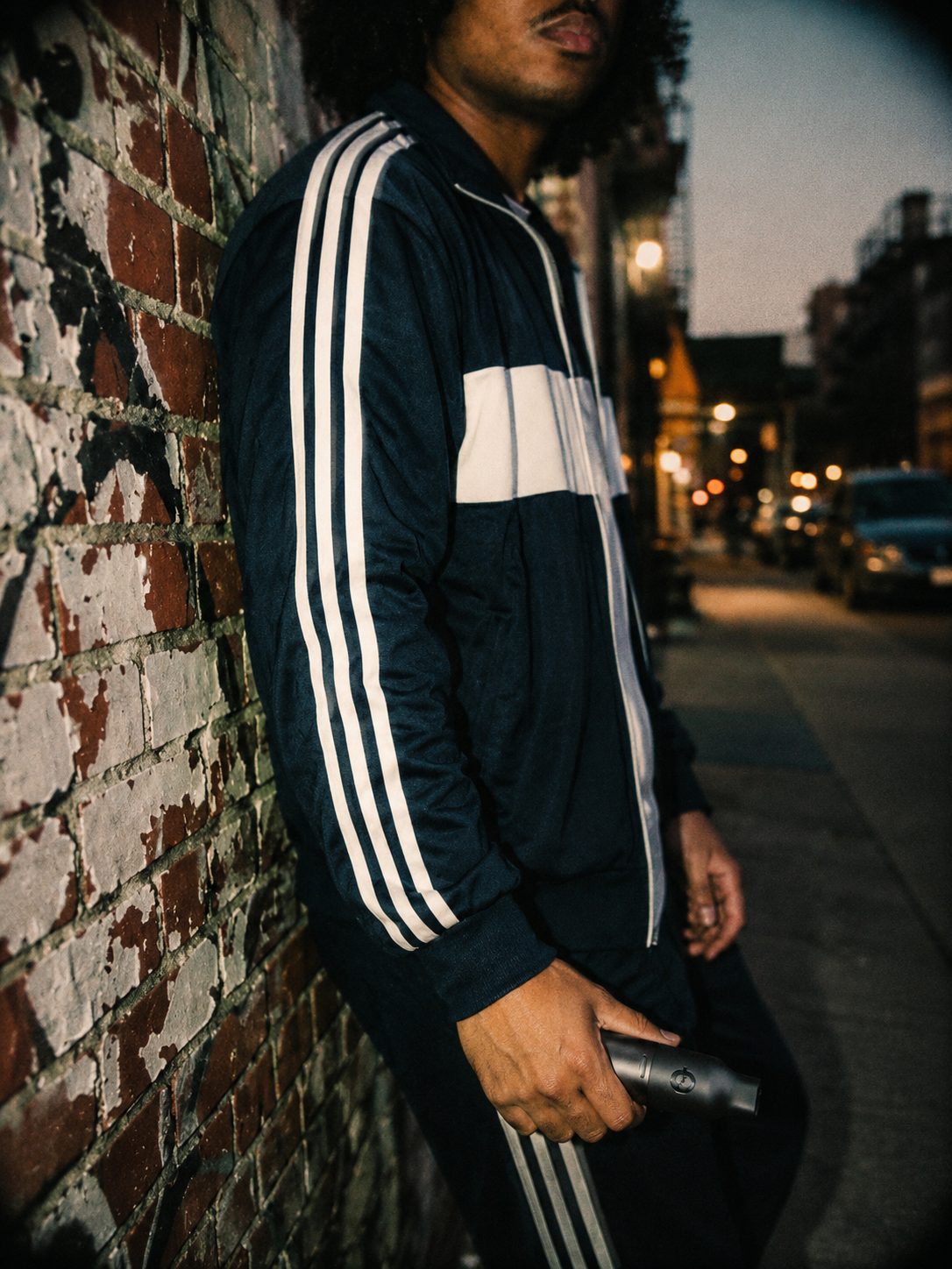 CAPNOS customer holding a nicotine-free device by a brick wall